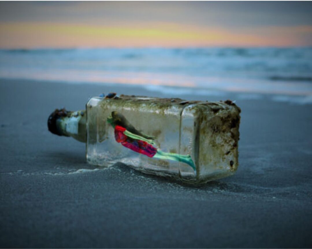 Une bouteille en verre échouée sur le sable au bord de l'eau, contenant une femme à l'interieur, symbolisant l'inspiration et les idées créatives.