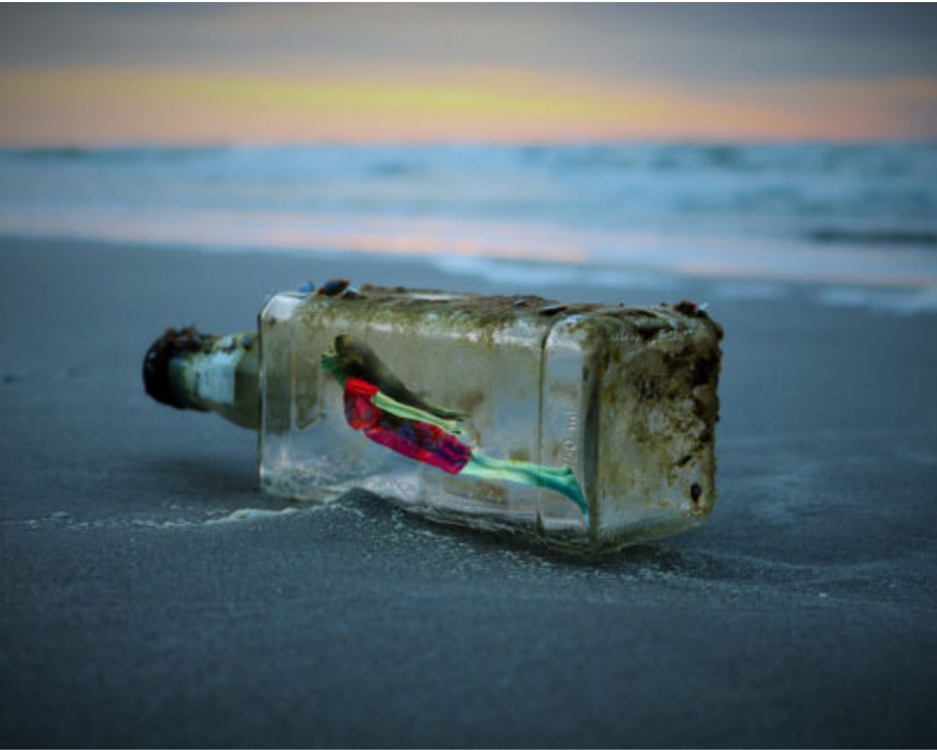 Une bouteille en verre échouée sur le sable au bord de l'eau, contenant une femme à l'interieur, symbolisant l'inspiration et les idées créatives.