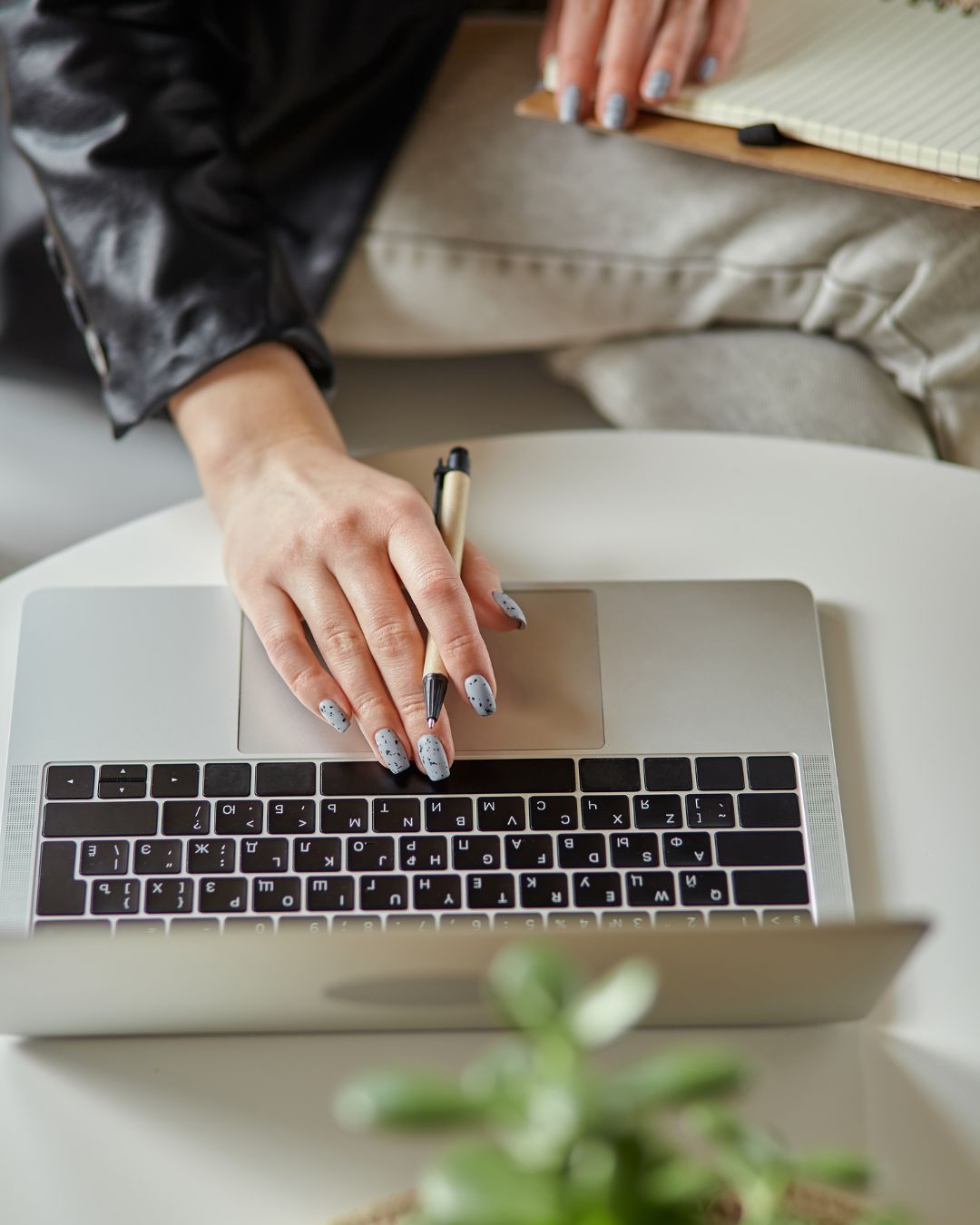 Vue en gros plan des mains d'une graphiste utilisant un ordinateur portable avec une tablette graphique, illustrant le travail de création de contenu.