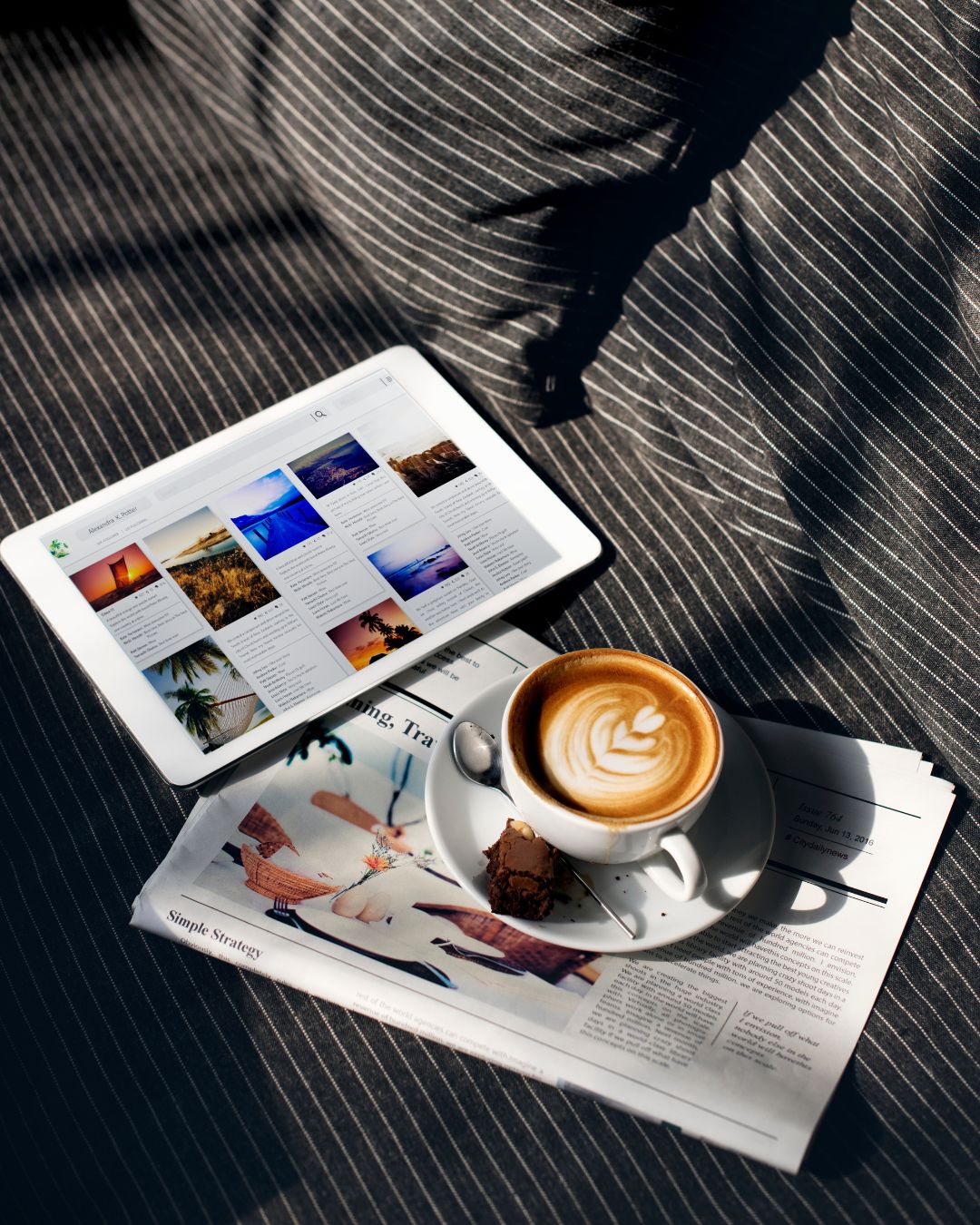 Une tablette numérique avec des photos et une tasse de café posées sur un journal, symbolisant la création et la lecture de contenu pour un blog