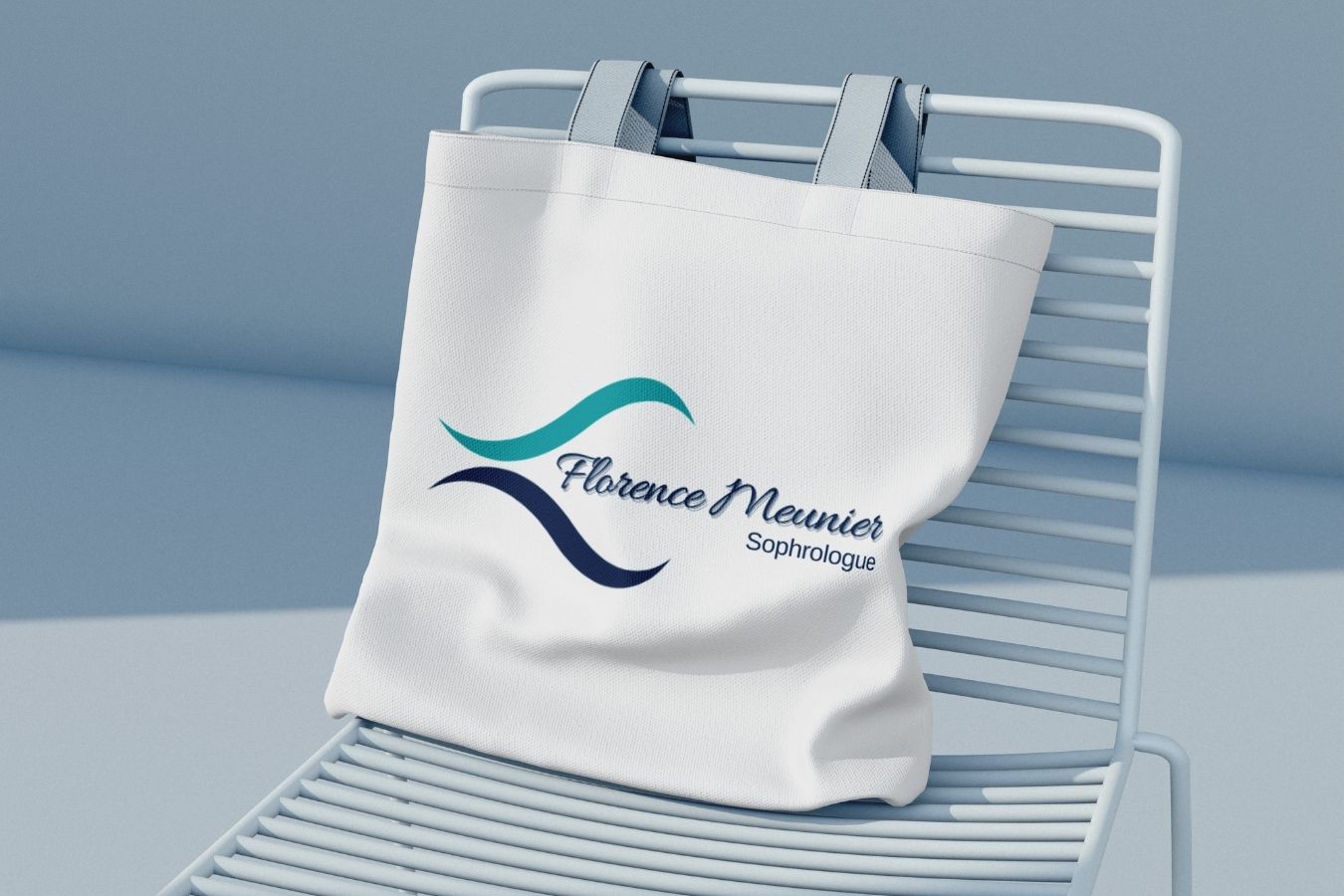 Logo Florence Meunier imprimé sur un tote bag en tissu blanc, posé sur une structure métallique minimaliste.