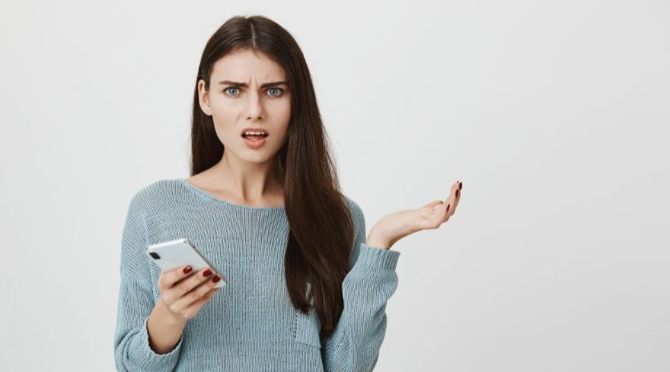 Une cliente confuse qui regarde son smartphone, montrant un problème de clarté dans la communication d'une marque.